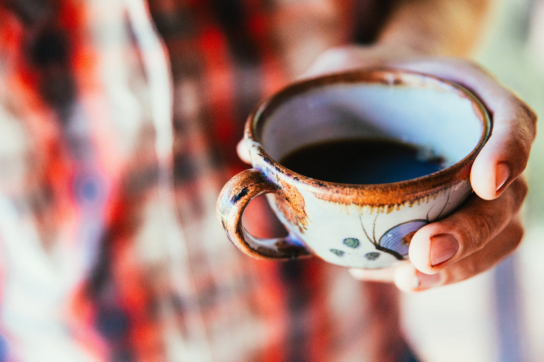 coffee cup in a mans hand with a shirt background