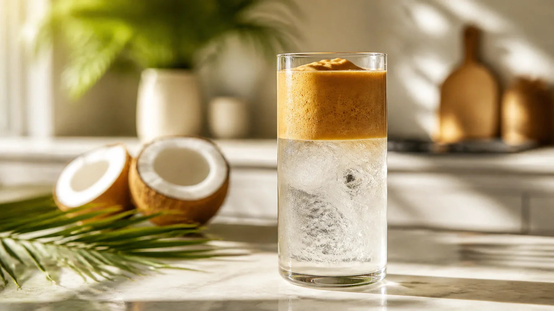 A tall glass of Tropical Buzz coconut water cloud coffee with a thick dark espresso foam floating over ice and coconut water, garnished with a pinch of sea salt.