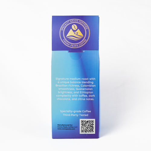 A tall, narrow coffee bag package standing upright on a white background. The packaging features a blue-to-light-blue gradient design with a gold circular logo at the top and product details printed in white text.