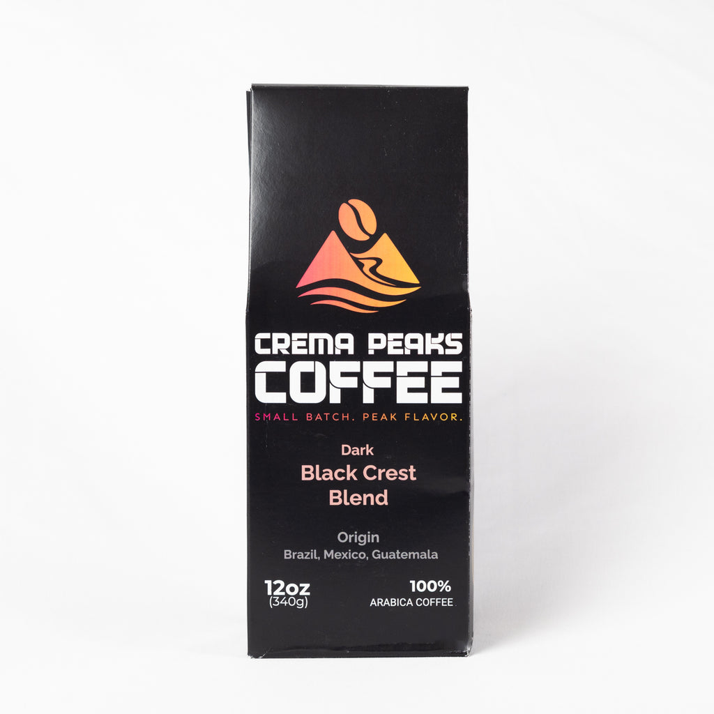 A tall black coffee box labeled Crema Peaks Coffee Dark Black Crest Blend, shown upright on a clean white background.