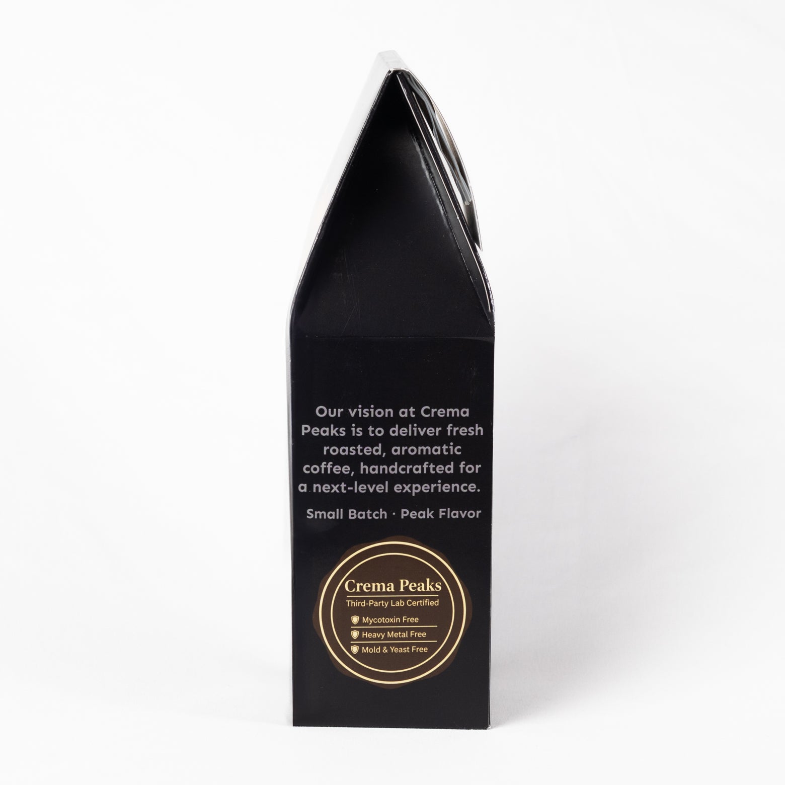A tall, black coffee bag package standing upright on a white background. The front features white descriptive text and a circular gold logo for Crema Peaks.