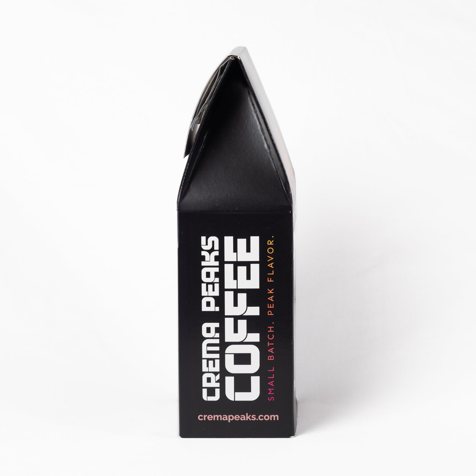 A black coffee bag package shown upright against a clean white background, with large white vertical text reading 'CREMA PEAKS COFFEE' and smaller pink text reading 'SMALL BATCH, PEAK FLAVOR.'.