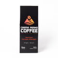 A tall, narrow black coffee package from Crema Peaks Coffee, featuring a colorful mountain logo and text for the Bold Dark Cerrado Midnight, on a clean white background.