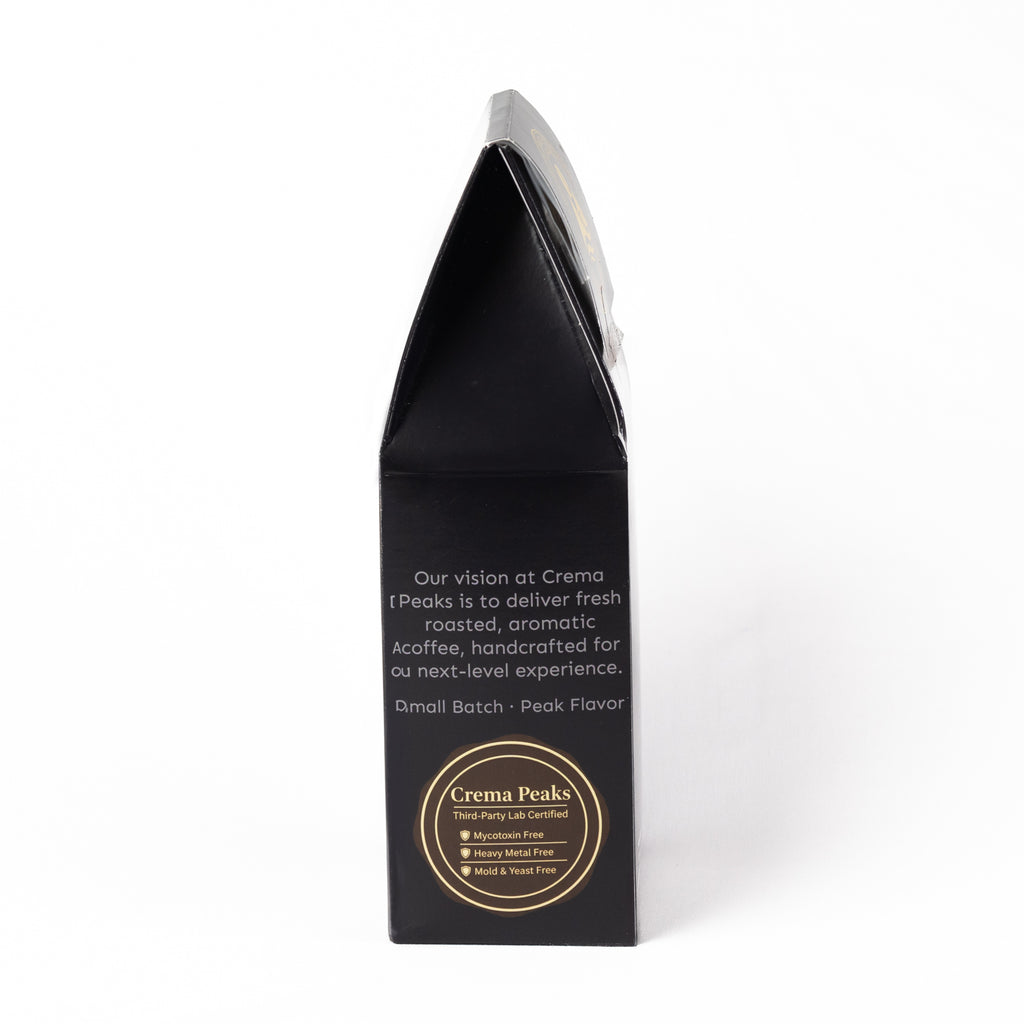 A tall, black coffee bag packaging box with white text and a gold circular logo at the bottom, photographed on a clean white background.