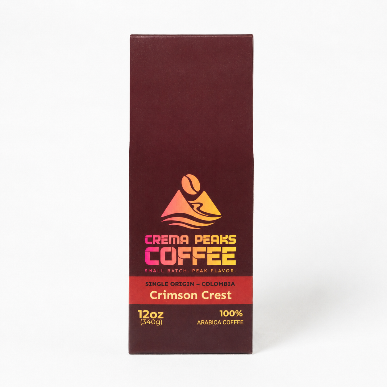 A tall, narrow box of Crema Peaks Coffee in the Crimson Crest single origin coffee, shown against a plain white background. The packaging is a deep maroon-brown color with a central graphic featuring a coffee bean, a mountain, and waves in yellow, orange, and pink, with text indicating it is a 12oz single-origin Colombian coffee.