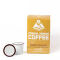 A box of Crema Peaks Coffee Light Golden Compass K-Pods next to two individual coffee pods on a clean white background.