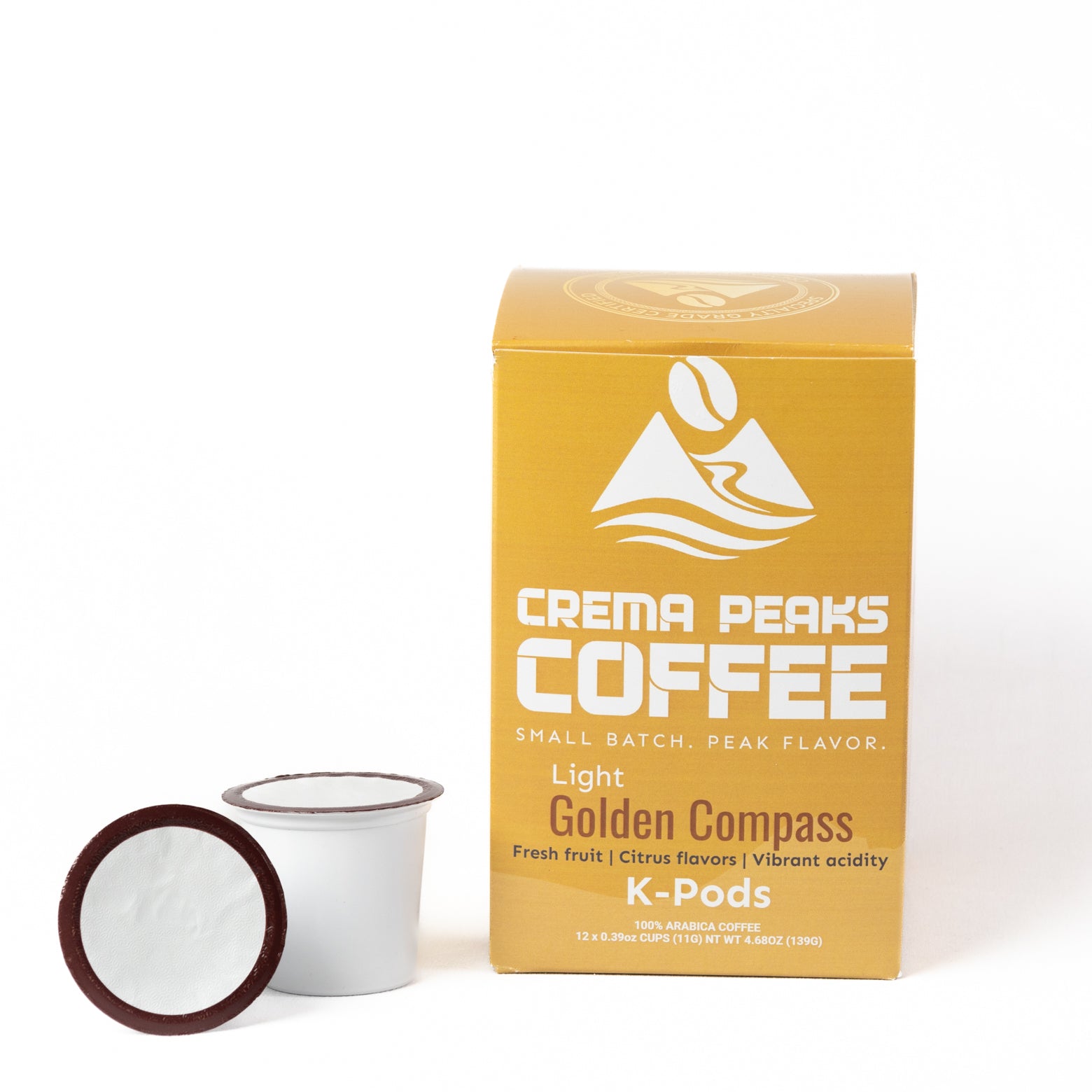 A box of Crema Peaks Coffee Light Golden Compass K-Pods next to two individual coffee pods on a clean white background.