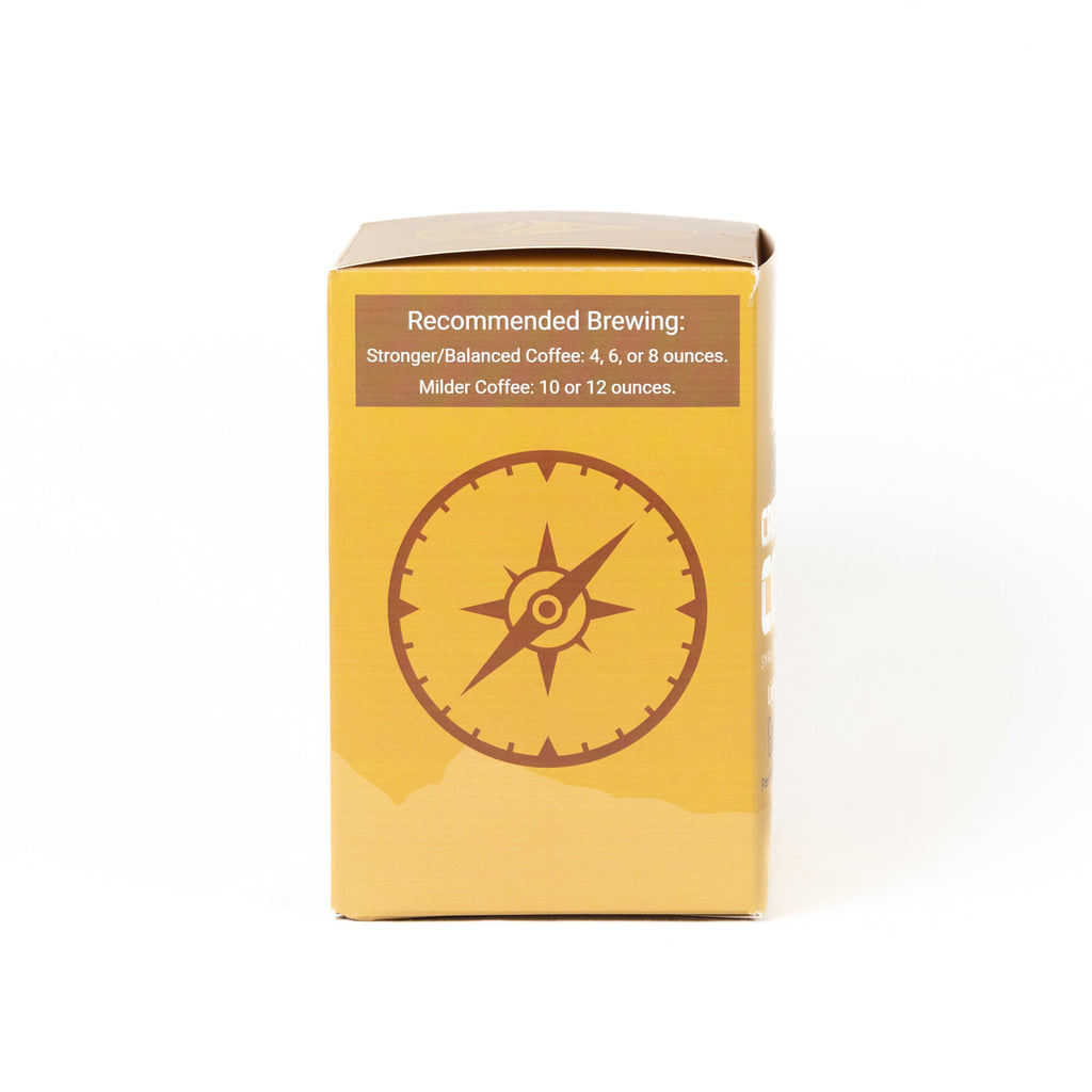 A yellow cardboard box with a brown compass graphic and brewing recommendations printed on the front, photographed against a plain white background.
