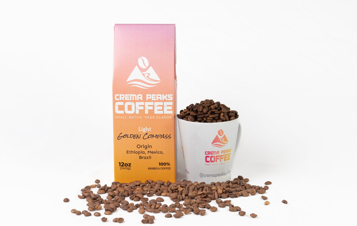 A package of Crema Peaks Coffee next to a white mug filled with coffee beans and scattered loose beans on a white background.