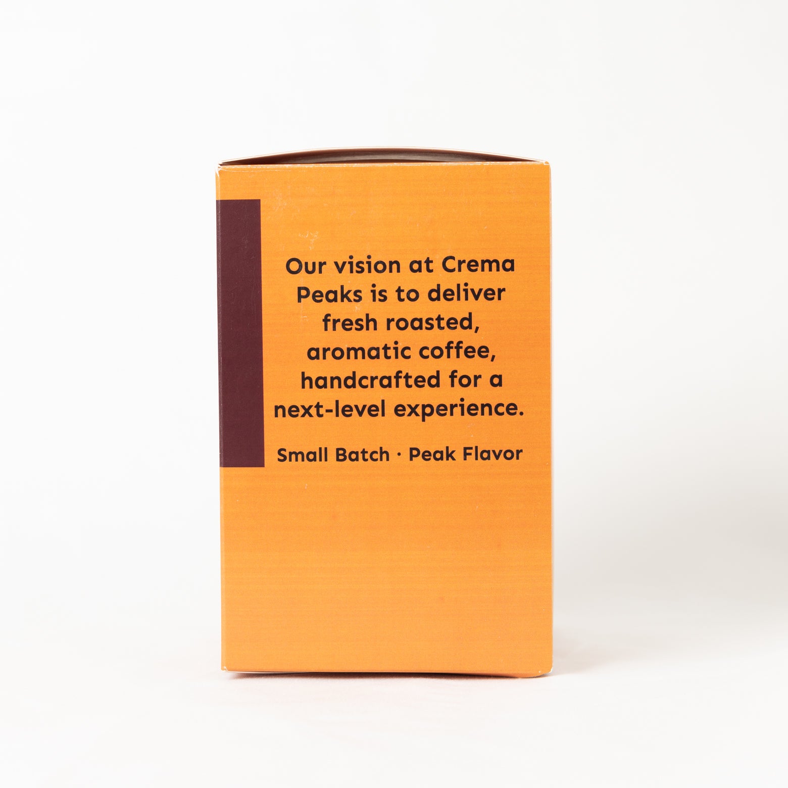 The back of a cream-colored cardboard coffee box with a dark brown vertical stripe on the left and black text, set against a plain white background.