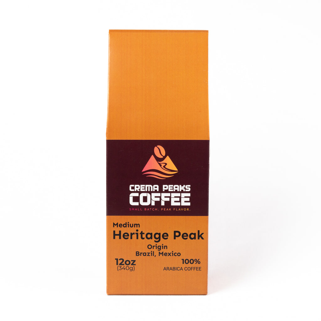 A 12 oz bag of Crema Peaks Coffee Medium Heritage Peak arabica coffee, featuring an orange and dark brown packaging design on a white background.