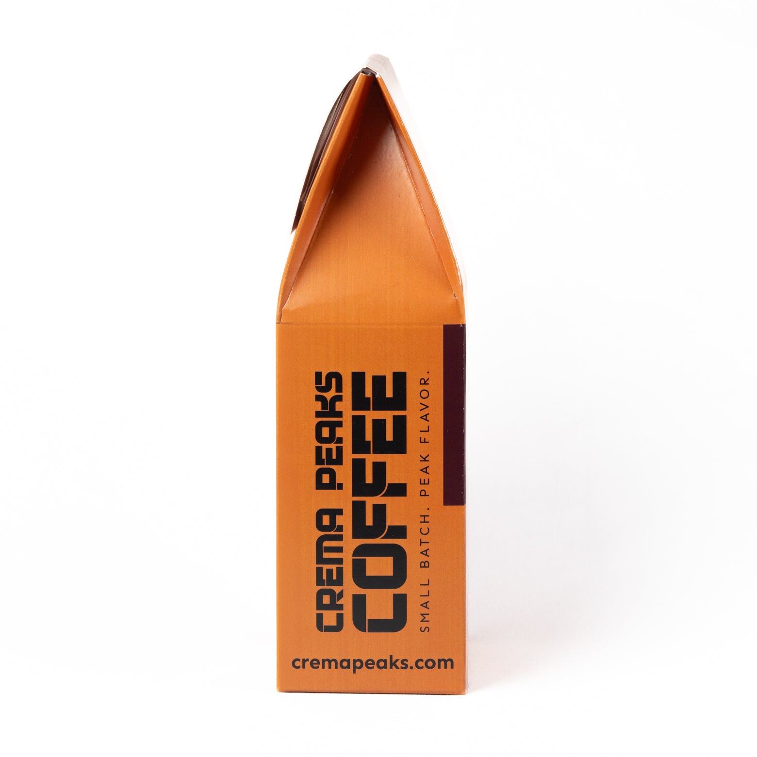 An orange coffee bag package from Crema Peaks Coffee, standing upright on a white background. The bag features bold black text reading 'CREMA PEAKS COFFEE' and 'SMALL BATCH, PEAK FLAVOR.