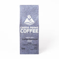 A tall, narrow coffee bag from Crema Peaks Coffee in the Indigo Sumatra Decaf coffee, featuring a textured slate-blue design with white text and logo, set against a plain white background.