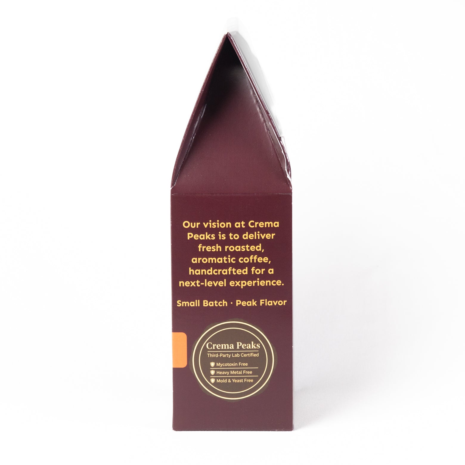 A tall, narrow cream-colored paperboard box shown from the back side, featuring yellow text and a circular gold and white logo for Crema Peaks on a plain white background.