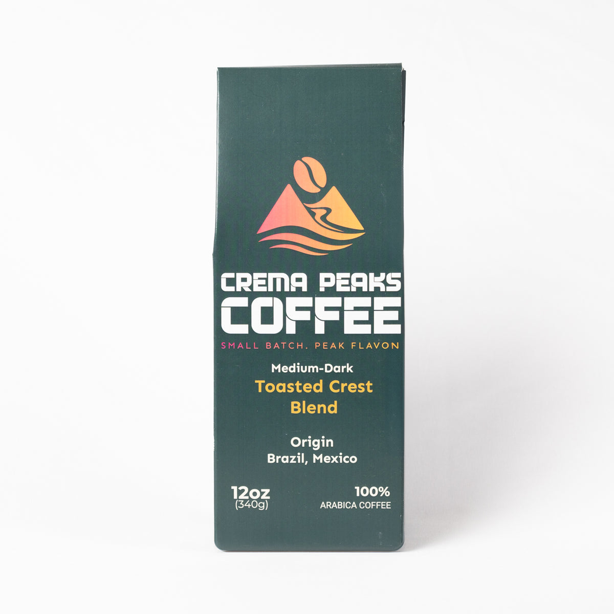 A tall, narrow package of Crema Peaks Coffee Medium-Dark Toasted Crest Blend, shown on a clean white background. The packaging is dark green with white and orange text and graphics.