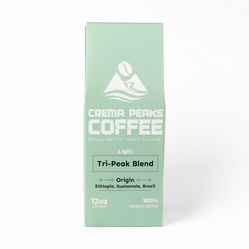 A mint green coffee box for Crema Peaks Coffee's Light Tri-Peak Blend, featuring white text and logo on a clean white background.