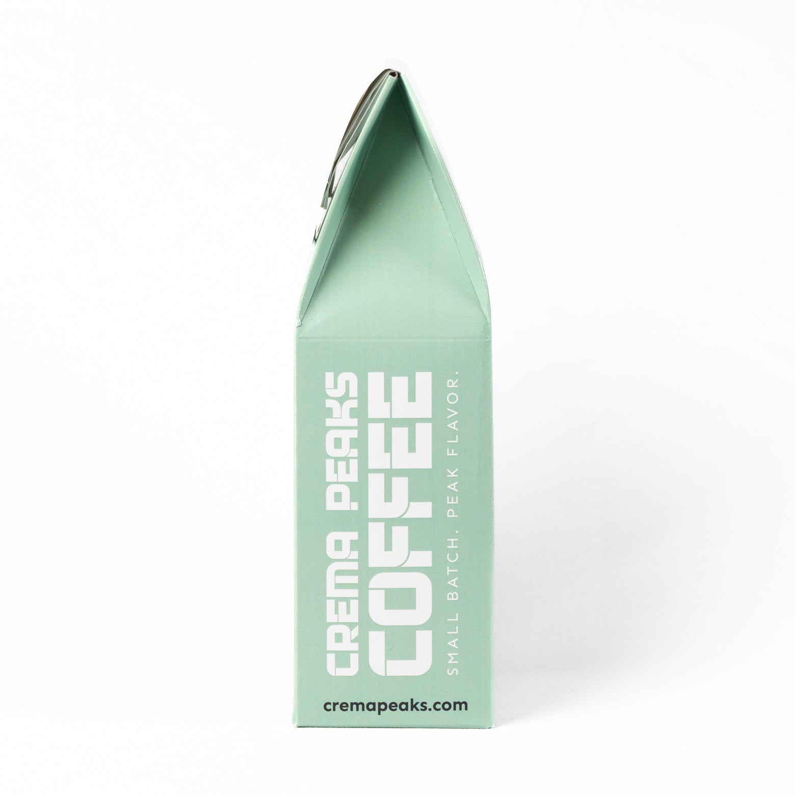 A mint green coffee bag package from Crema Peaks Coffee, shown upright against a clean white background. The packaging features bold white text reading 'CREMA PEAKS COFFEE' and smaller text 'SMALL BATCH PEAK FLAVOR.